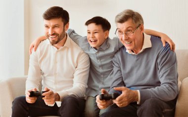 Hafta sonu. Üç kişilik neşeli erkek aile içeride koltukta oturmuş video oyunu oynuyorlar. Seçici Odaklanma