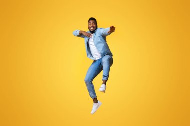 Çekingenliğinle savaş. Komik Afrikalı Amerikalı adam atlıyor ve sarı arka planda serbest alan ile karate hareketleri yapıyor