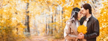 Bir demet altın yapraklı romantik aşıklar sonbahar ormanlarında sarılıyorlar.