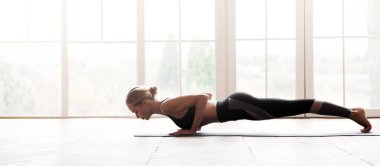 Güçlü vücut. Yanında yoga yapan genç bir kadın, evde egzersiz yapan, fotokopi alanı olan bir panorama.