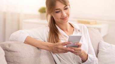 Akıllı Telefon Okuyan Neşeli Kadın Girişimci Salonda Oturan Haberleri Okuyor. Seçici Odaklanma