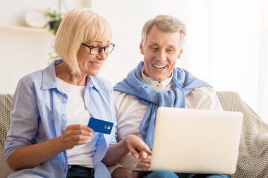 İnternetten alışveriş. Üst düzey eşler dizüstü bilgisayarda alışveriş yapıyor, kredi kartı tutan kadınlar...