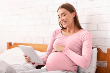 Pozitif Hamile Kadın Dijital Tablet Kullanıyor E-Kitap Okuyor Ya da Yatak Odasında Oturan Film İzliyor