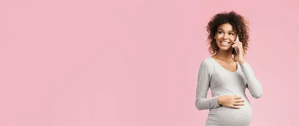 stock image Excited pregnant woman talking on smartphone, having pleasant conversation on pink background, copy space