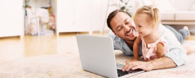 Modern Çocukluk Konsepti. Neşeli baba ve sarışın çocuk dizüstü bilgisayarda yerde uzanmış çizgi film izliyorlar.