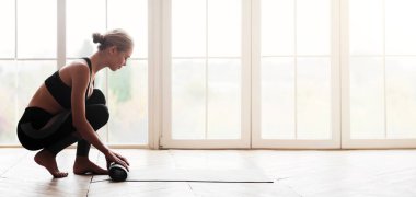 Yoga yaptıktan sonra genç ve çekici bir kadının yan görüntüsü, yoga minderi, beyaz tavan arası stüdyo arka planı, fotokopi odası.