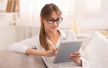 İçerideki koltukta oturan rahat bayan dijital tablet kullanıyor. Hafta sonu evde. Seçici Odaklanma