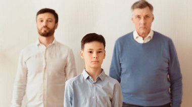 Nesiller Arası Yanlış Anlama. Çocuk, baba ve büyükbaba beyaz arka planda kameraya bakıyor. Panorama, Seçici Odaklanma