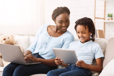 Teknoloji Konsepti. Mutlu siyah aile kanepede oturuyor, evde dizüstü bilgisayar ve dijital tablet kullanıyorlar, boş yer var.