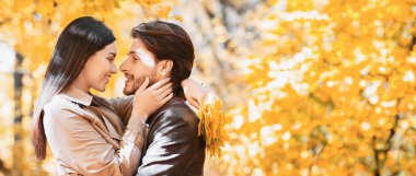 Sevgi dolu kız, altın parkta sarılıp yatarken yakışıklı erkek arkadaşının yüzüne dokunuyor.