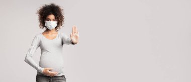 Bulaşıcı hastalıklar ve grip. Tıbbi maskeli hamile kadın dur işareti veriyor, gri arka plan