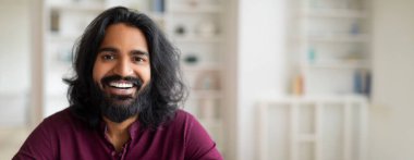 Kameraya bakan yakışıklı, neşeli, genç Hintli bir adamın portresi, pozitif milenyum doğulu erkek evin içinde poz veriyor, gülümseyen sakallı bir milenyum adamının yakın çekimi, kopyalama alanı.