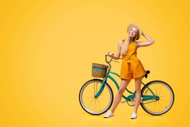 Yaz Planları. Sarı Arkaplan üzerinde klasik bisikletin yanında duran Dalgın Genç Kızın Portresi, Kopya Alanı olan Panorama