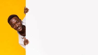 Handsome african guy looking out white blank board for advertising, panorama