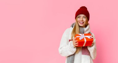 Sarışın, kırmızı şapkalı, sarı arka planda Noel hediyesi tutan, içi boş bir panorama olan güzel bir kız.