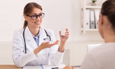 Gülümseyen Kadın Doktor Ofiste Hasta için Reçete Yazan Tedaviyi Öneriyor.