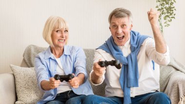 Evde video oyunlarında yarışan, hafta sonları eğlenen olgun bir çift.