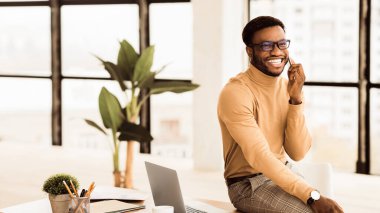 İletişim Konsepti. Modern ofiste siyahi işadamı cep telefonuyla konuşuyor. Kopyalama alanı olan Panorama
