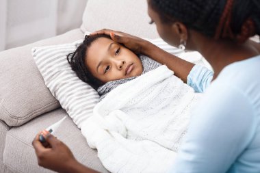 Ateş Konsepti. Hasta çocuk yatakta, annesi termometreyi tutuyor, zavallı kızı teselli ediyor.