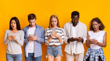 Sorunlu akıllı telefon kullanımı. Sarı arka plan ve panorama üzerinde cep telefonu kullanan çok ırklı bir grup genç.