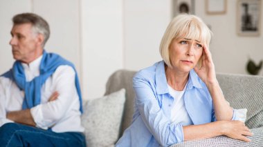 Kocası ile tartıştıktan sonra üzgün yaşlı kadın, oturma odasında kanepede oturan