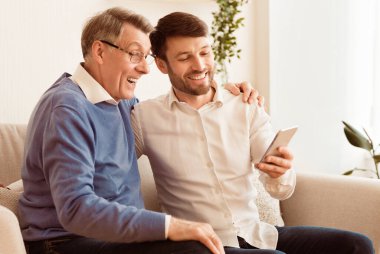 Olgun oğul, babaya koltukta otururken cep telefonunu kullanmayı öğretiyor. Seçici Odaklanma