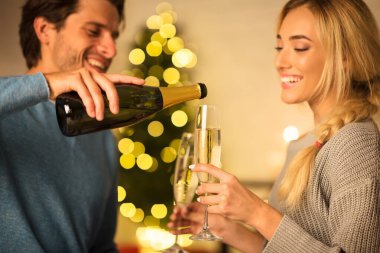 Adam bardaklara şampanya dolduruyor, evde eşiyle Noel 'i kutluyor.