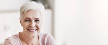 Portrait of senior business woman smiling at camera, home interior