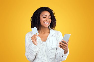 İnternetten alışveriş. Kredi kartı tutan Afro kız, internetten akıllı telefon satın alma ürünleri kullanıyor.