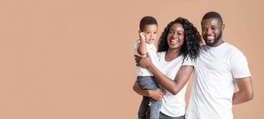 Mutlu afro-yıl ebeveynlerinin portresi. Küçük şirin bir oğlu var. Sarı arka planda boş alan var.