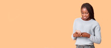 Güzel alet ve başvuru formu. Bej arka plan, fotokopi alanı ve panorama üzerinde akıllı telefon kullanan gülümseyen Afrikalı Amerikalı kadın.