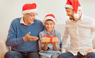 Mutlu çocuk, babasından ve dedesinden Noel hediyesi alıyor. Evde koltukta oturuyor. Xmas Tatil Sezonu. Seçici Odaklanma