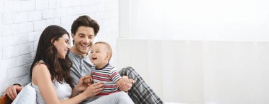 Neşeli bir aile sıcak bir oturma odasında birlikte oturur, güler ve oynar. Ebeveynler neşeli çocuklarına sevgi dolu bir şekilde bağlanırlar. Mutlulukla dolu sıcak ve neşeli bir atmosfer yaratırlar.