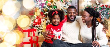 Noel arifesi. Xmas için dekore edilmiş neşeli afro aile portresi, birlikte gülerek ve kış tatillerinin tadını çıkararak.