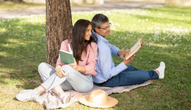 Bir çift, bir ağacın altındaki battaniyeye oturmuş, kitaplarına dalmış. Güneşli bir günde huzurlu bir anı paylaşıyorlar. Huzurlu bir park ortamında birbirlerine eşlik ediyorlar..
