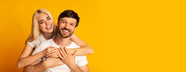 Радостная пара широко улыбается, обнимая друг друга, демонстрируя свою любовь и счастье. Ярко-желтый фон усиливает тепло момента, копирует пространство