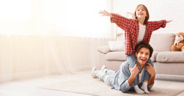 Mutlu çocukluk kavramı. Baba ve küçük kız hafta sonunu evde birlikte geçiriyorlar, küçük kız babasıyla dönüyor, uçağı taklit ediyor, uzayı kopyalıyor.
