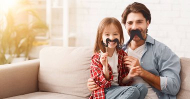 Güzel, komik küçük kız ve babasının evde poz veren bıyıkları var. Aile tatilleri ve birliktelik kavramı, kopyalama alanı