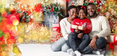 Noel aile portresi. Mutlu Afro-Amerikan babası, annesi ve kızı dekore edilmiş oturma odasında Xmas ağacının yanında poz veriyor.