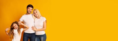 Neşeli bir aile, birlikte geçirdiğimiz bir anı gülümseme ve şakacı hareketlerle yakalar. Baba, anne ve kız yakın dururlar, günlük giysiler içinde beyaz gömlekler ve kot pantolon, kopyalama alanı