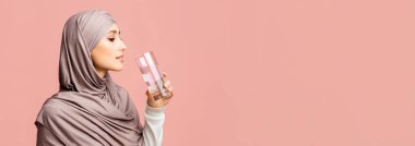 Hidrasyon konsepti. Türbanlı Müslüman Kadın Temiz Su İçiyor Pembe arka planda Boş Alan, Panorama