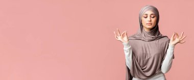 Zen. Rahat Müslüman kız tesettüre dalmış, gözleri kapalı meditasyon yapıyor, parmaklarını Mudra jestinde tutuyor pembe arka plan üzerinde boş alan ile.