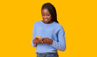 Güzel alet ve başvuru formu. Sarı arka planda akıllı telefon kullanan gülümseyen Afrikalı-Amerikalı kadın, kopya alanı, panorama