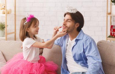 Küçük tatlı anaokulu kızı babasına ruj sürüyor. Genç baba taç takıyor, bugün prenses günü.