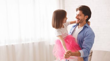 Sevgi dolu baba ve küçük prenses kız evde vals yapıyor, baba kızı tutuyor.