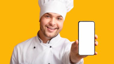 Yemek Teslimatı Uygulaması. Şef Adam, Sarı Stüdyo Arkaplan 'da yemek servisi öneren boş ekranlı telefonu gösteriyor. Panorama