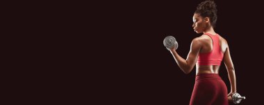 Siyah fitness kadını dambıllarla egzersiz yapıyor, arka plan, siyah stüdyo arka plan, kopya alanı olan panorama