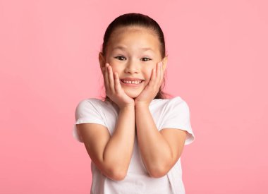 Vay canına. Yanaklarına dokunan heyecanlı Asyalı çocuğun yakın plan portresi. Pastel mor stüdyo duvarı üzerinde izole edilmiş.