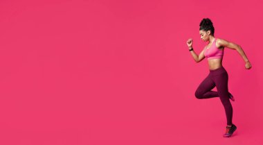 Sportif Afrikalı kadın fitness modeli. Kırmızı stüdyo arka planında egzersiz yapıyor. Zıplıyor.