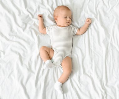Bodysuit sevimli yenidoğan bebek kolları ile beyaz battaniye üzerinde uyuklama, üst görünüm, kopya alanı